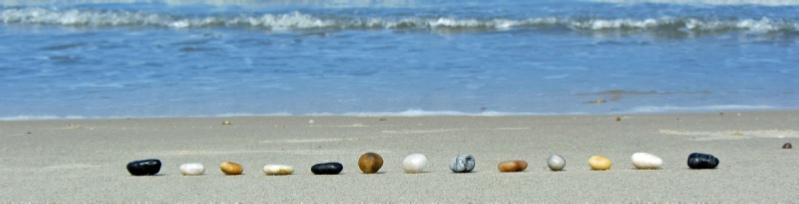 eine gerade Reihe von bunten Steinen liegt am Strand, im Hintergrund das Wasser und heranbrechende Wellen, Andreas Bertram-Weiss ǀ Mehr-Blick - Angebote an Supervision - am Bodensee, im Thurgau, der Ostschweiz und Baden-Württemberg